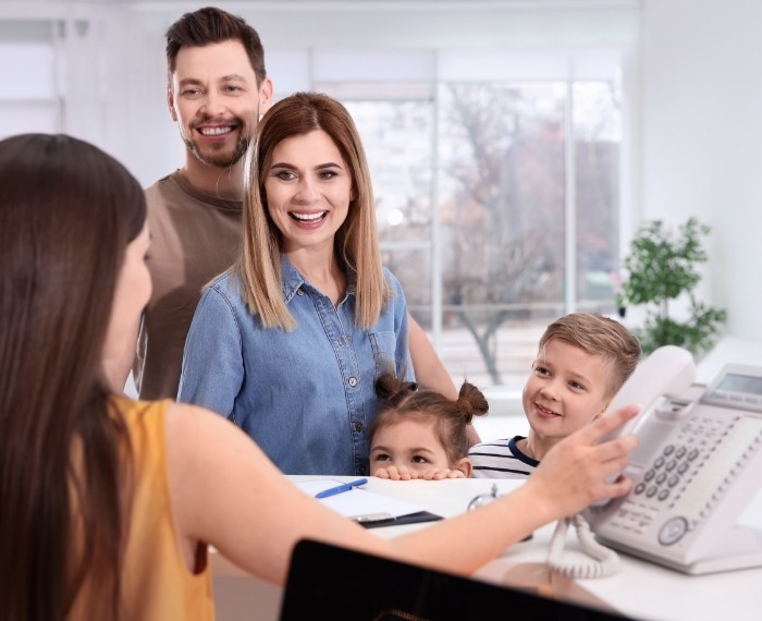 Family smiling at dental office reception desk