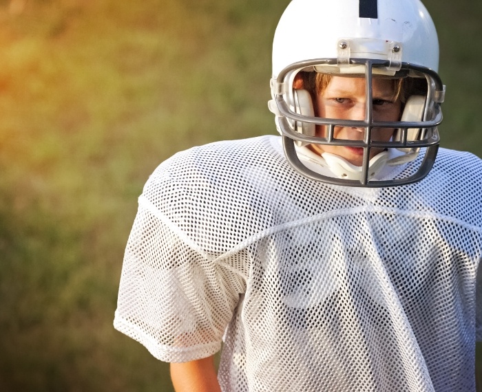 Child in football uniform with athletic mouthguards