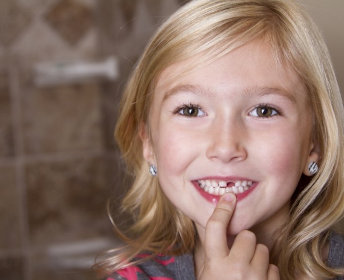 Child pointing to smile after tooth extraction