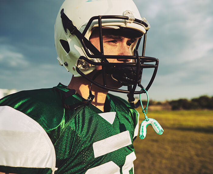 Teen in football uniform with athletic mouthguard