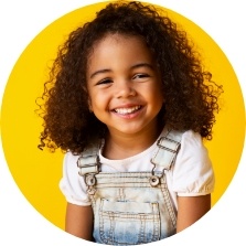 Young girl in white overalls grinning