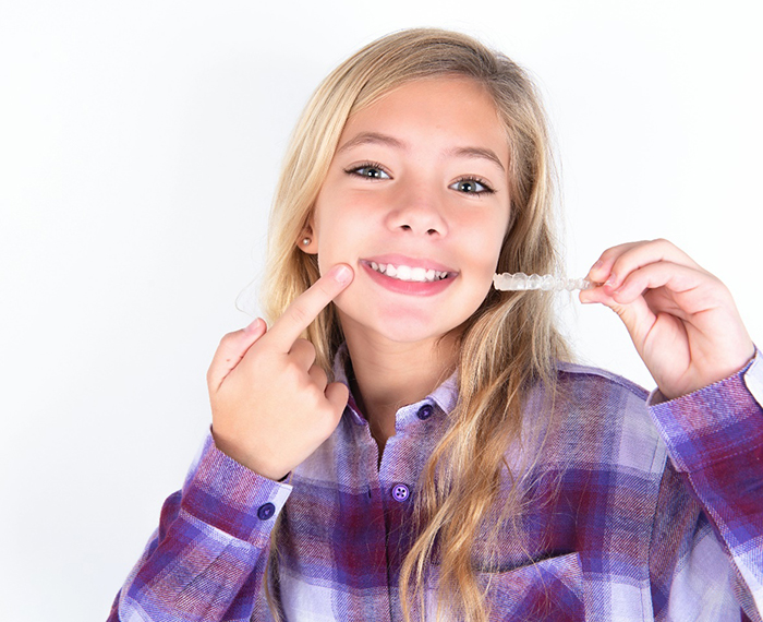 Teenage girl holding aligner for Invisalign in Danville, CA