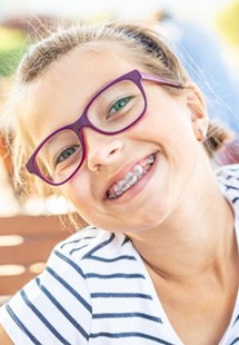 a girl smiling while wearing traditional braces