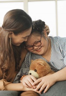 a girl with special needs smiling with her mother