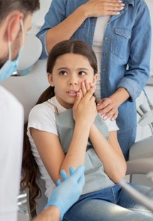 a child holding her cheek due to tooth pain