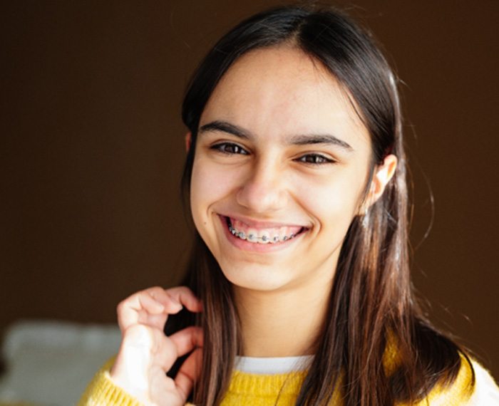 Teen with braces smiling in yellow sweater