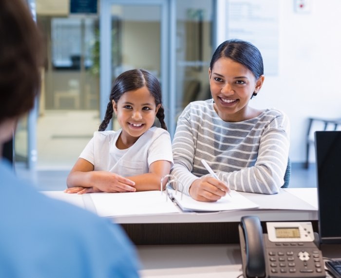 Mother and child discussing the cost of treating dental emergencies with dentistry patient