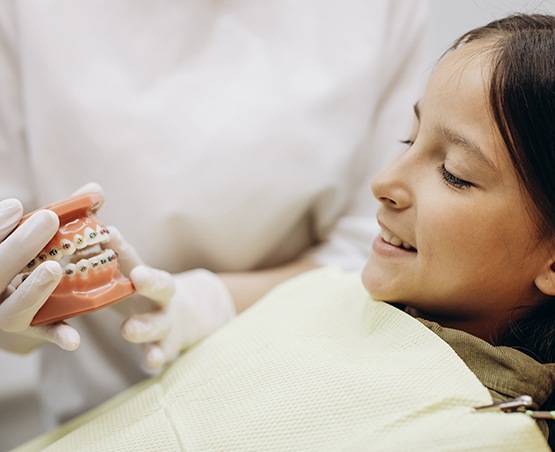 an orthodontist showing a child a model of a mouth